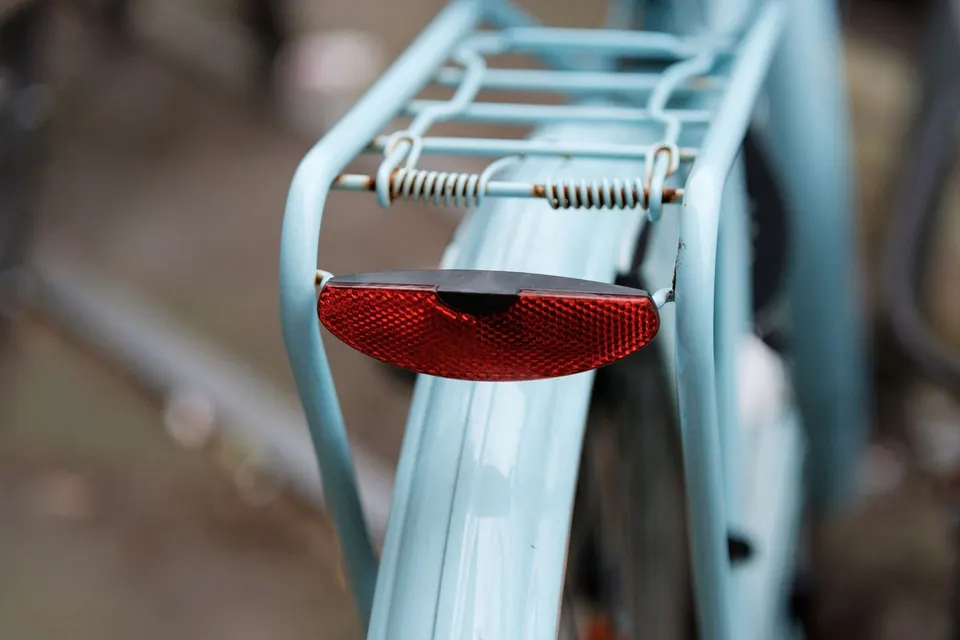 Garde-boue arrière bleu ciel d’un vélo de ville, sous le porte-bagages et son catadioptre rouge