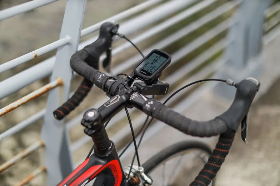 Compteur GPS fixé au cintre d’un vélo de route noir et rouge