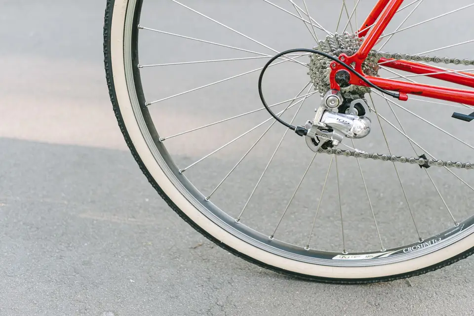 Roue arrière d’un vélo de route rouge, pneu à flancs clairs, cassette et dérailleur