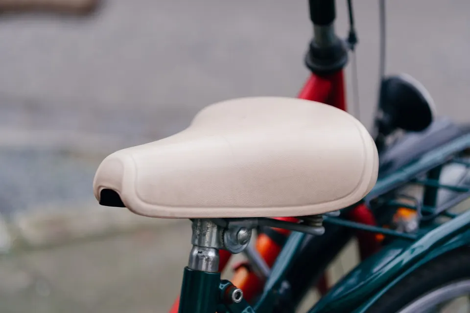 Selle de vélo de ville large et rembourrée, de couleur crème, sur un vélo vert foncé