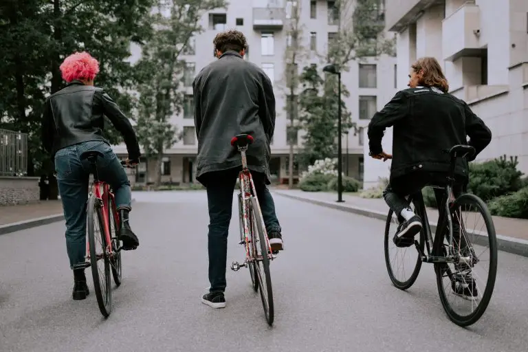 Trois personnes de tailles différentes avec un vélo adapté à leur taille attendent un pied à terre.